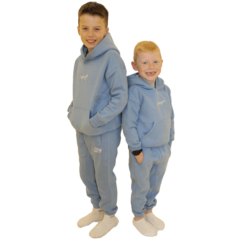 Two children wearing matching blue hoodie and sweatpants sets.