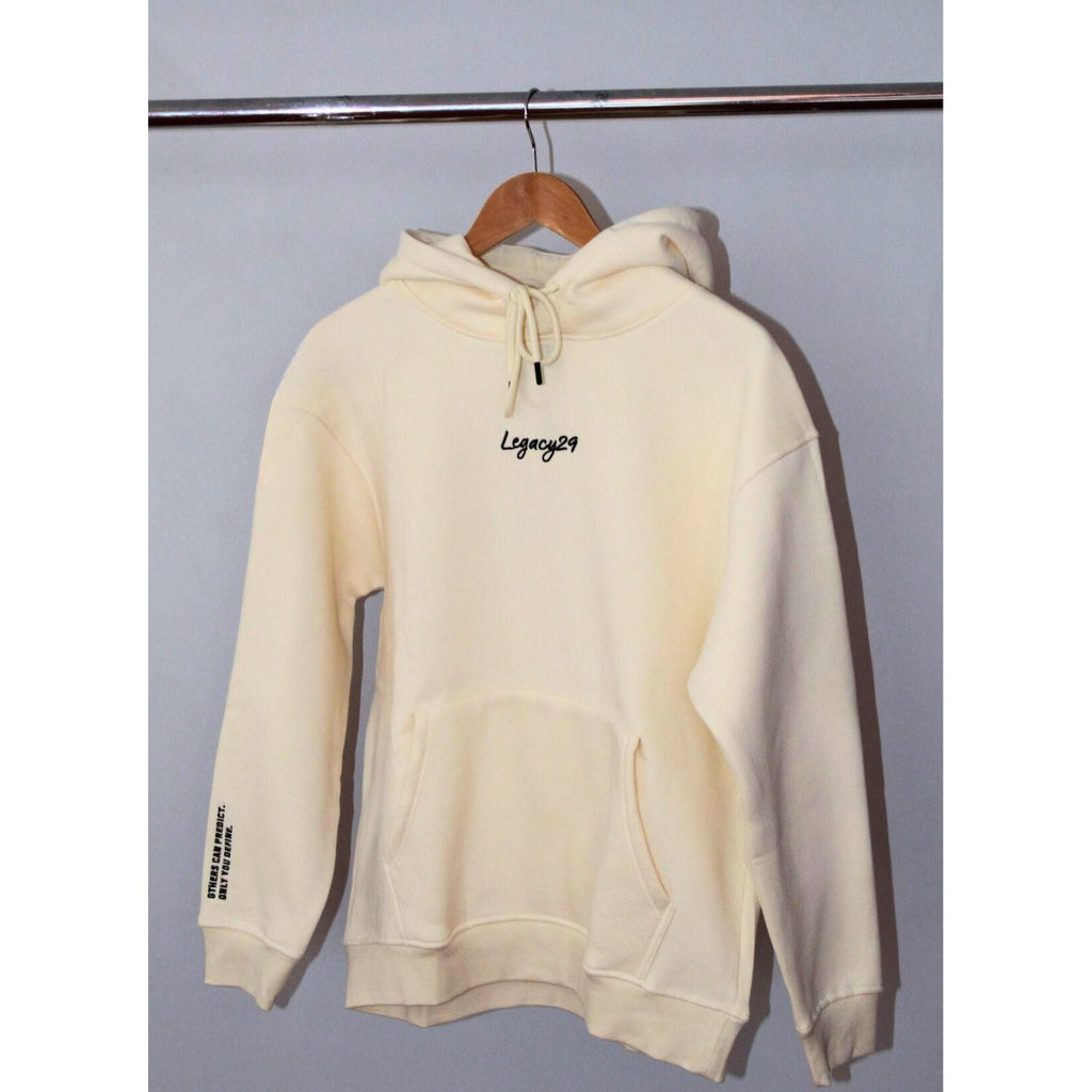 Legacy29 Cloud 9 cream hoodie hanging on a wooden hanger. Soft oversized design with embroidered logo on the chest, offering comfort and resilience.