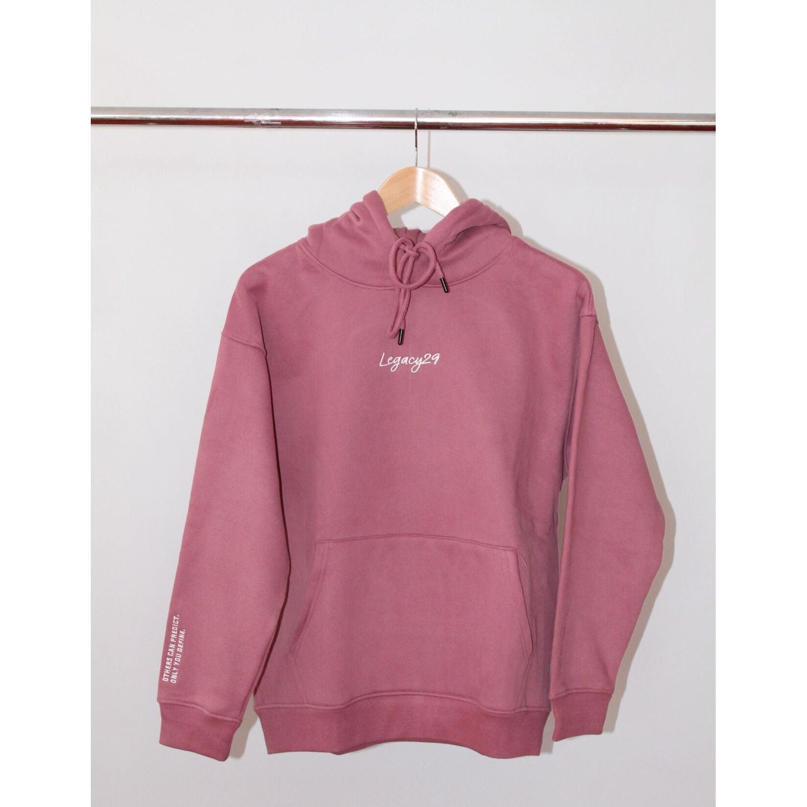 Legacy29 Resilient Ruby Red Hoodie hanging on a wooden hanger. Soft fabric with embroidered logo on chest, designed for comfort and resilience.