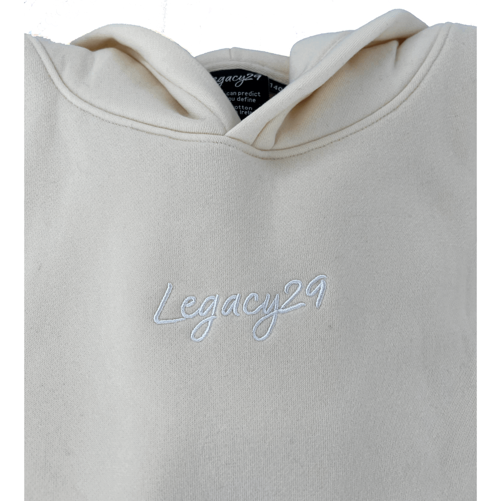 Close-up of Legacy29 Junior Cream Hoodie showcasing embroidered logo detail. Premium cotton fabric ensures comfort and durability.