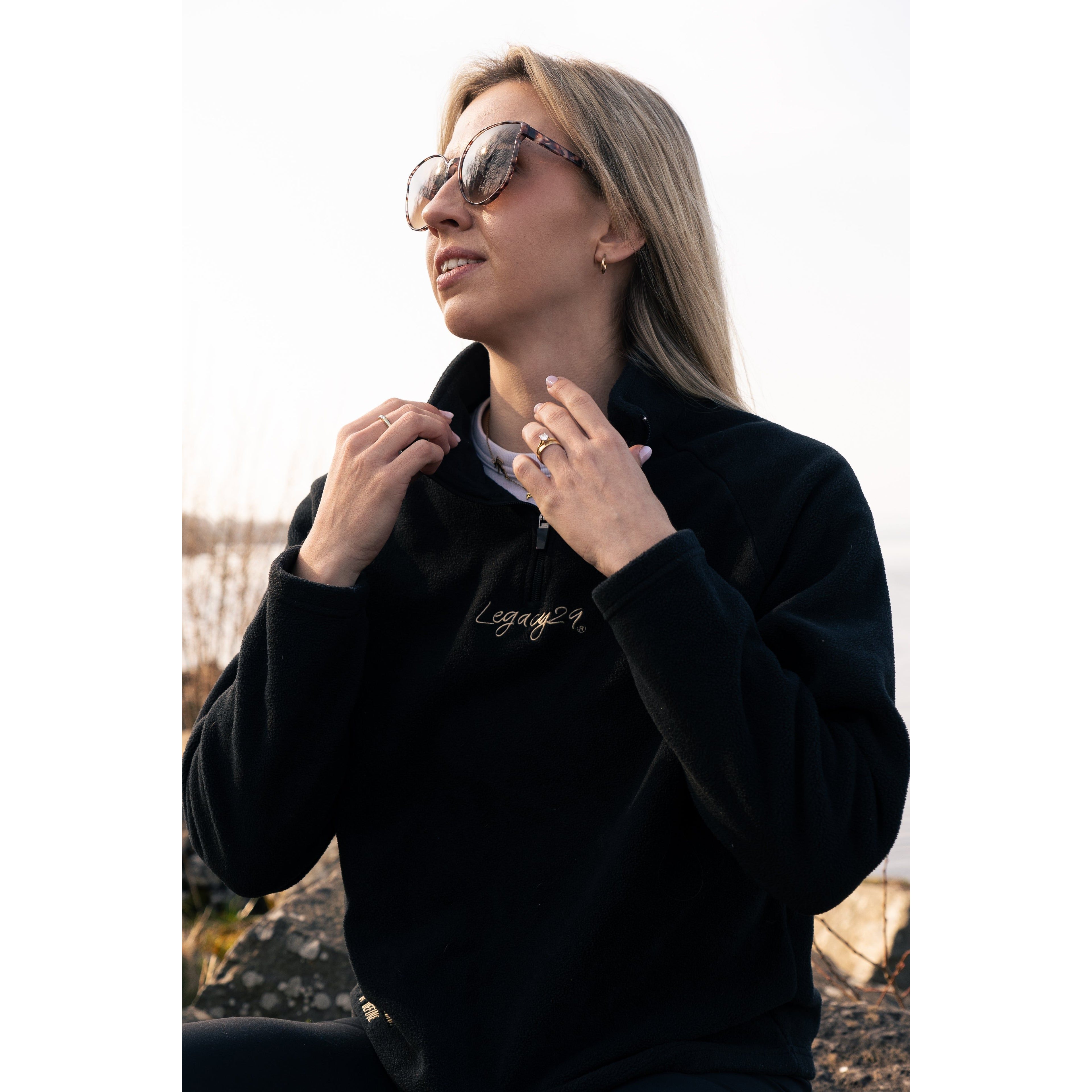 Model adjusting the collar of the Legacy29 Obsidian Black Fearless Fleece, emphasizing its cozy fit and premium mental health awareness design.