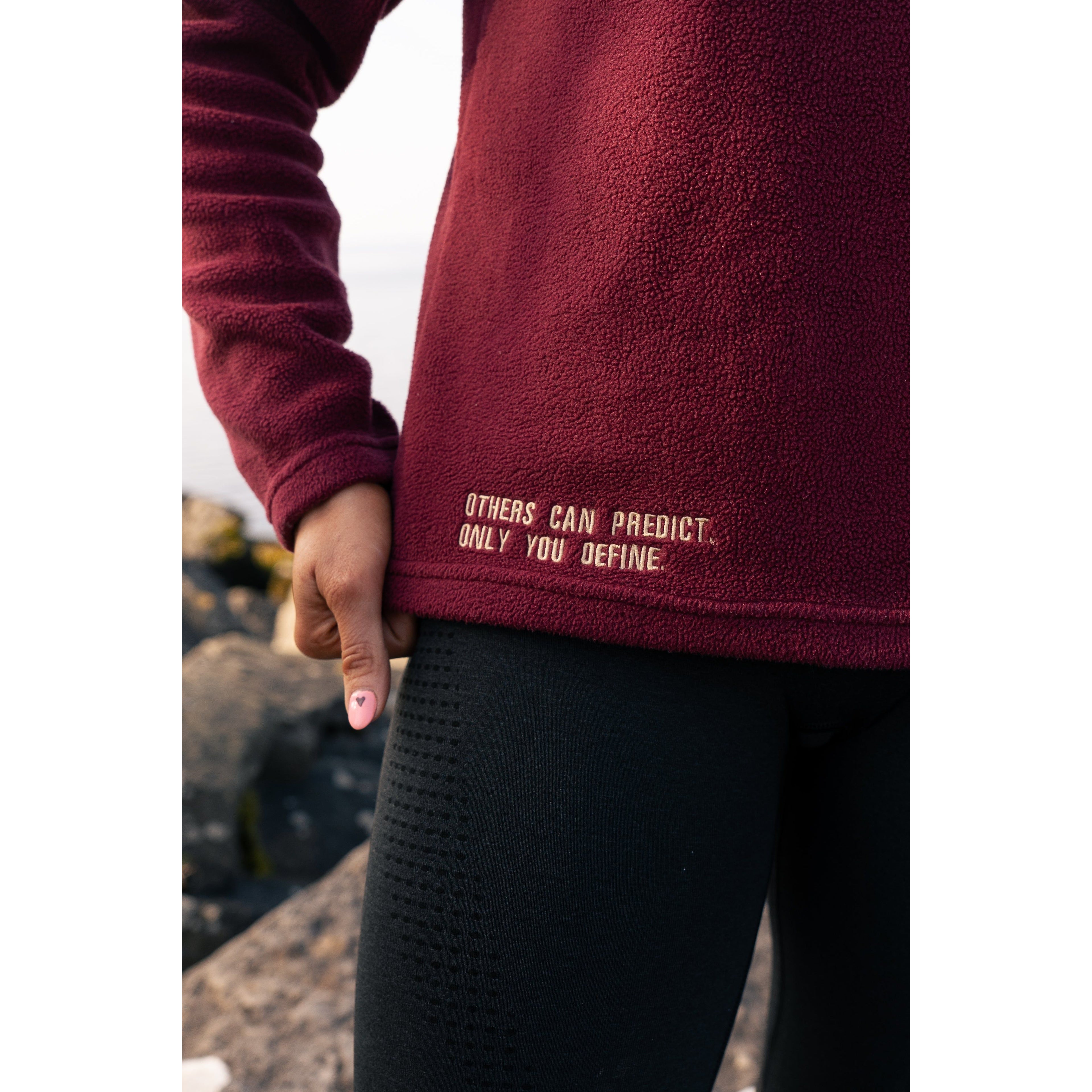 Close-up of Legacy29 Garnet Red Fearless Fleece showcasing the embroidered message, 'Others Can Predict, Only You Define,' promoting self-empowerment.