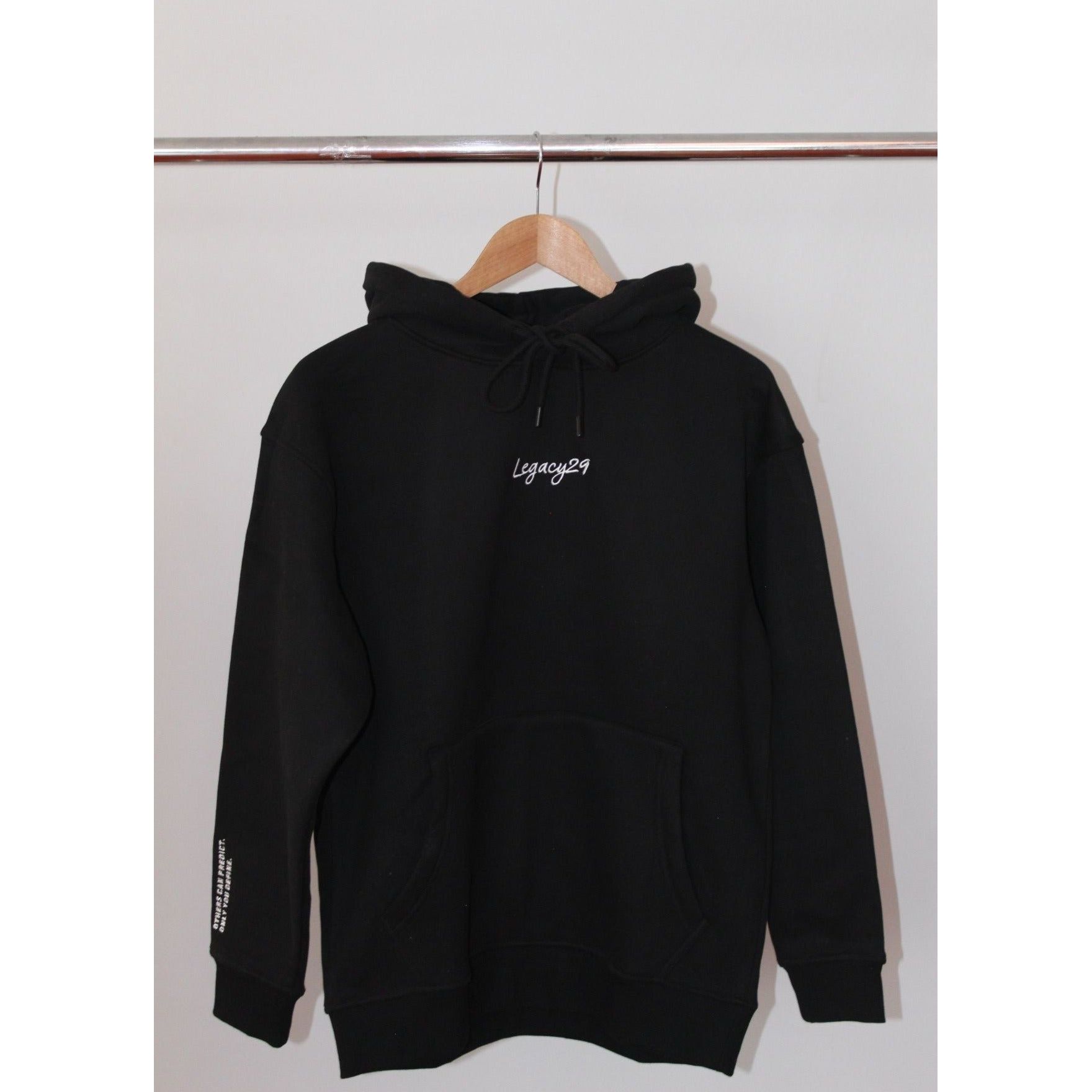 Legacy29 Bold Beginnings Black Hoodie hanging on a wooden hanger. Premium comfort hoodie with embroidered logo, designed for resilience and warmth.