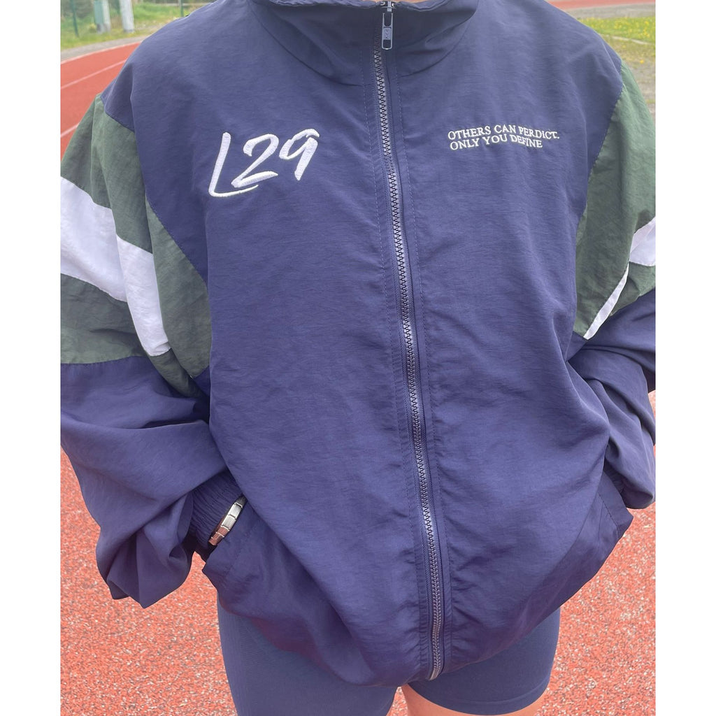 Person wearing a blue and green jacket with 'L29' on it, standing outdoors.