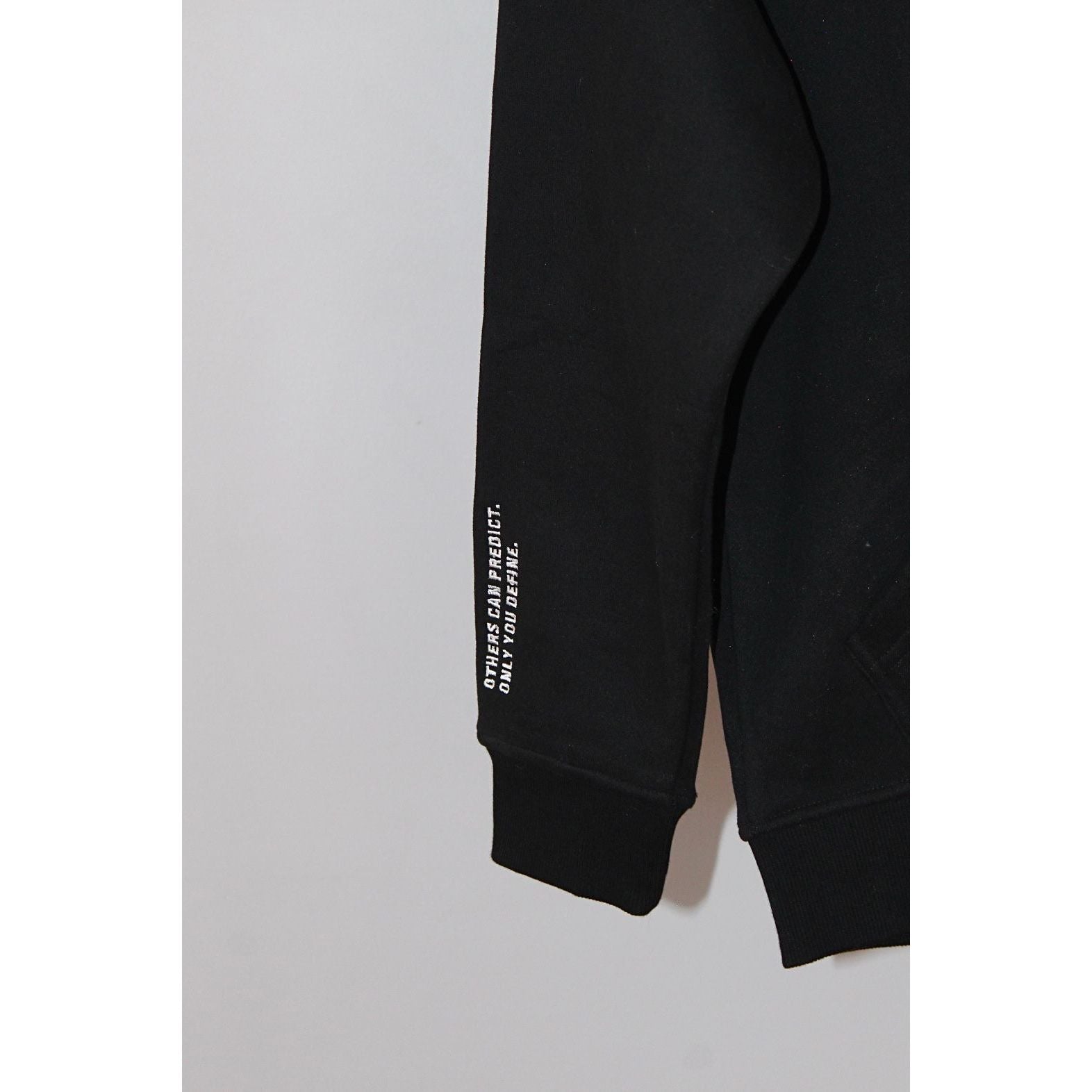 Close-up of sleeve detail on Legacy29 Bold Beginnings Black Hoodie. Features an inspiring printed message, emphasizing resilience and strength.