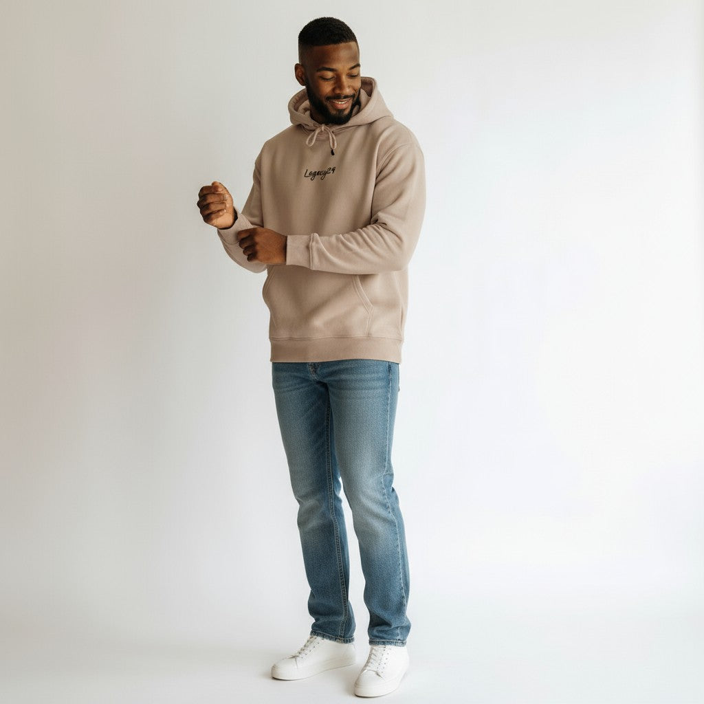 Man wearing a beige hoodie and blue jeans on a white background