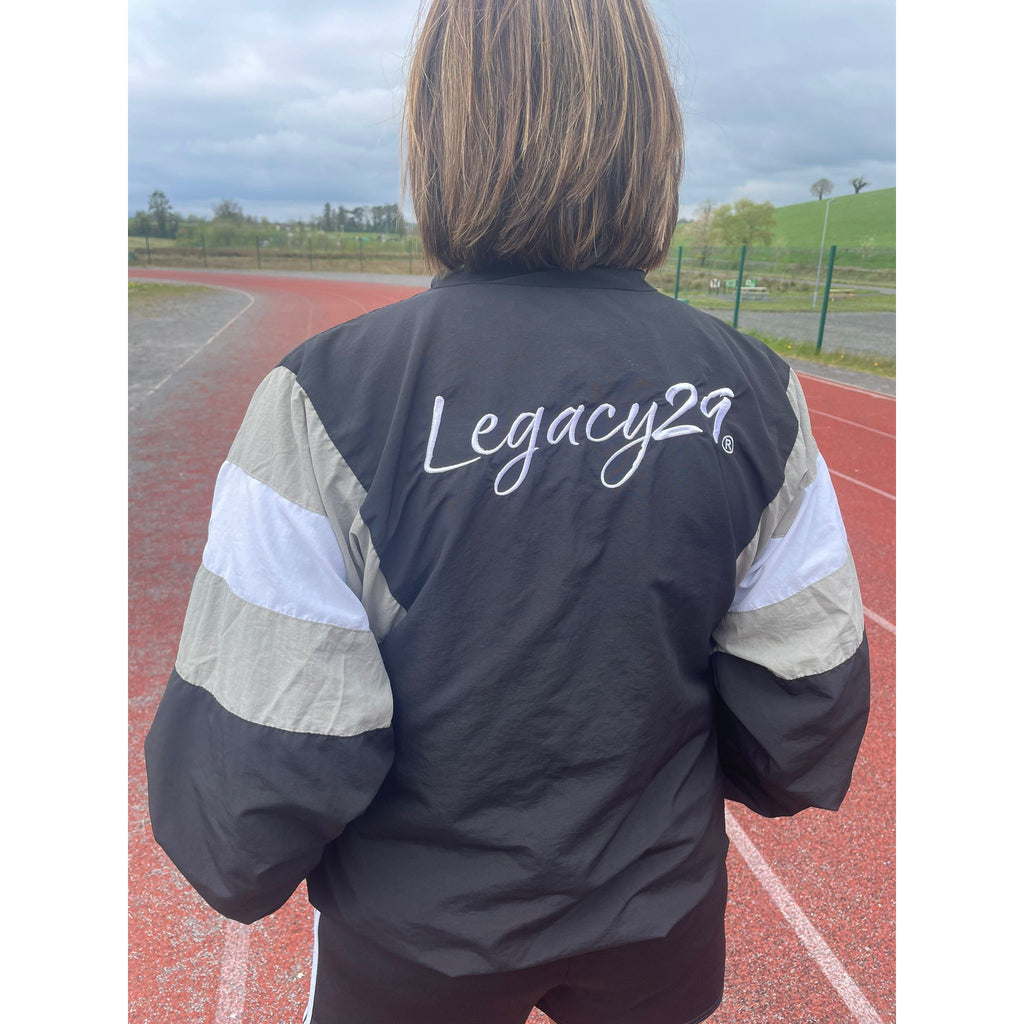 Person wearing a jacket with 'Legacy29' on the back, standing on a track.