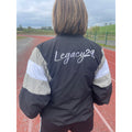 Person wearing a jacket with 'Legacy29' on the back, standing on a track.