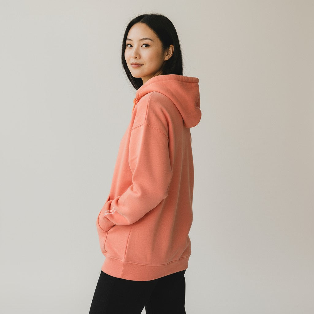 Person wearing a coral hoodie against a plain background