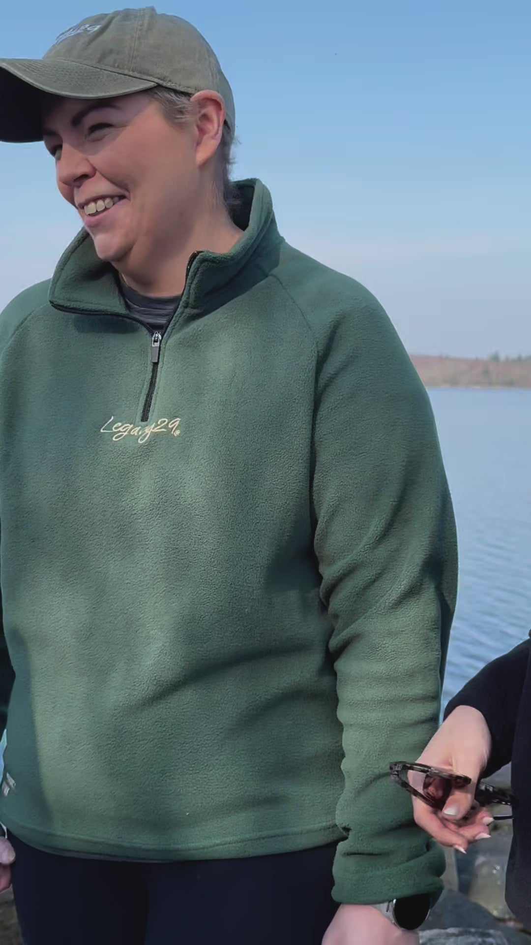 A person smiling while wearing the Emerald Green Fearless Fleece by Legacy29 near a lake. A warm and stylish fleece promoting mental health awareness.