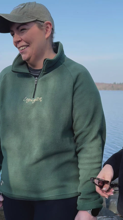 A person smiling while wearing the Emerald Green Fearless Fleece by Legacy29 near a lake. A warm and stylish fleece promoting mental health awareness.