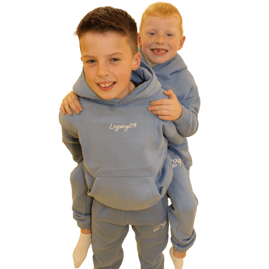 Two happy kids in the Legacy29 Junior Blue Comfort Set, showcasing the stylish hoodie and tracksuit bottoms. Ideal for comfortable kids' fashion.
