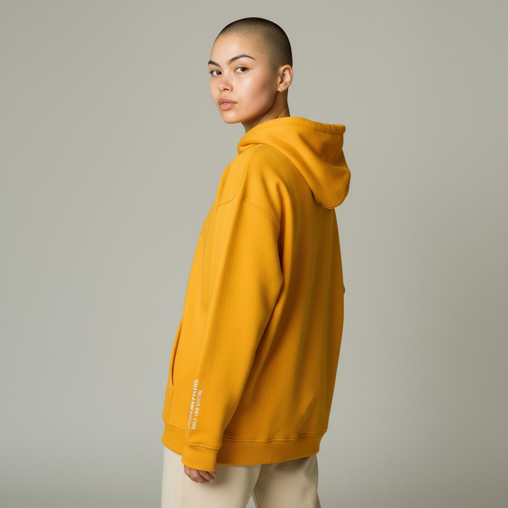 Person wearing a mustard yellow hoodie on a plain background