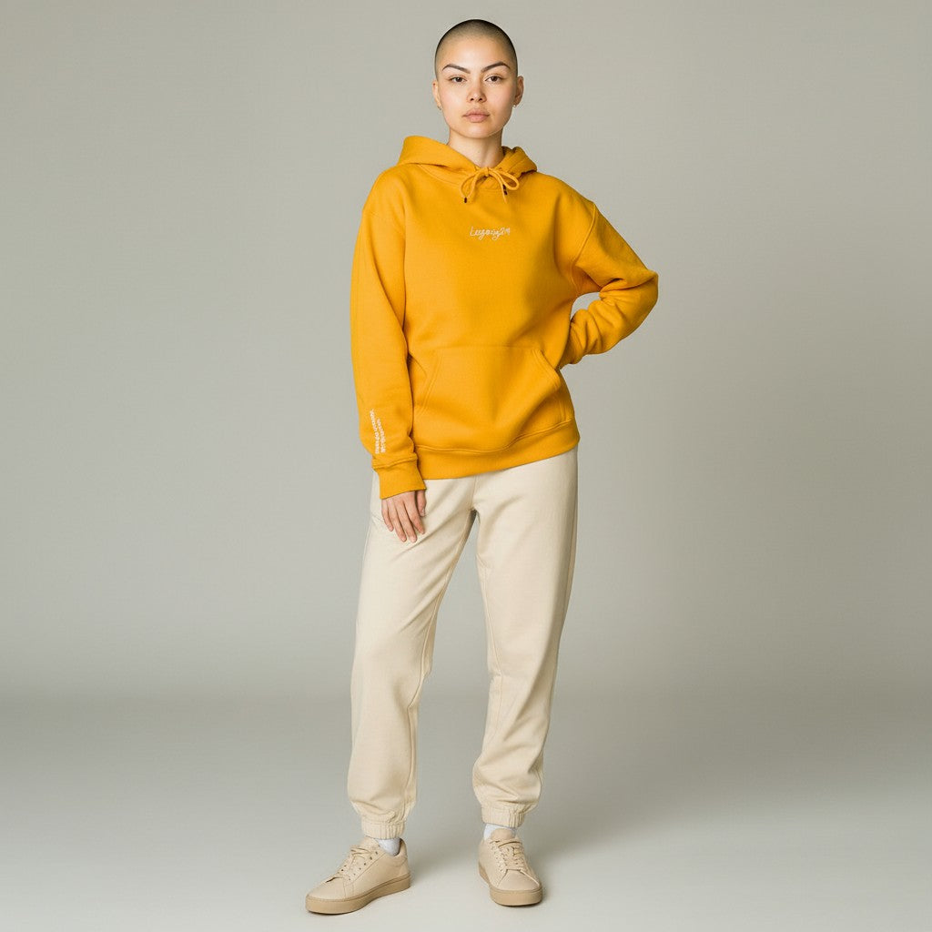 Person wearing a mustard yellow hoodie and beige pants on a plain background